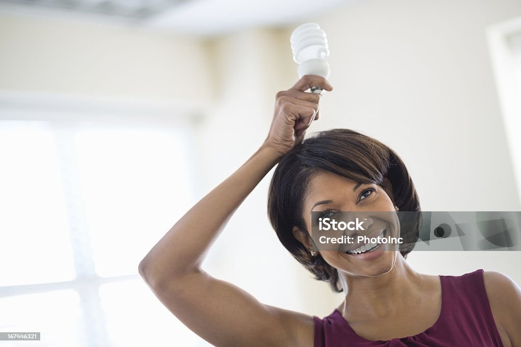 Heureuse Femme d'affaires tenant ampoule au-dessus de la tête - Photo de Ampoule électrique libre de droits