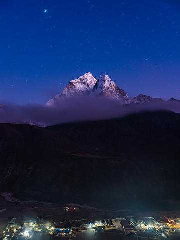 Stars shining above the snow capped peak of Ama Dablam overlooking the Sherpa teahouses in the Khumbu valley high in the Himalayan mountains of Nepal.