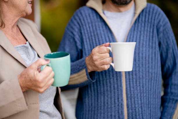 Young couple enjoying coffee in their cozy home, looking out a window, sharing a relaxed moment of togetherness