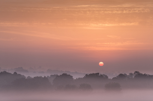 Sunrise looking toward Holy Trinity Church  and the village of Long Melford near Sudbury Suffolk UK. A misty morning on September.