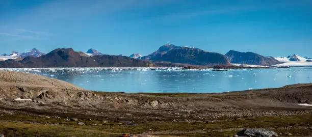 Photo of Landing on the shores of the spectacular Kongsfjorden, Spitsbergen, Svalbard, Norway. In the background on the left, the iconic three crown mountain (Tree Kroner) peaks