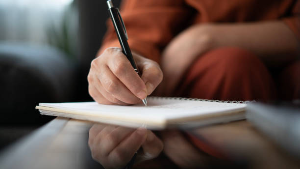 istock Close-up Adult woman taking notes while working on laptop at home 1674494077