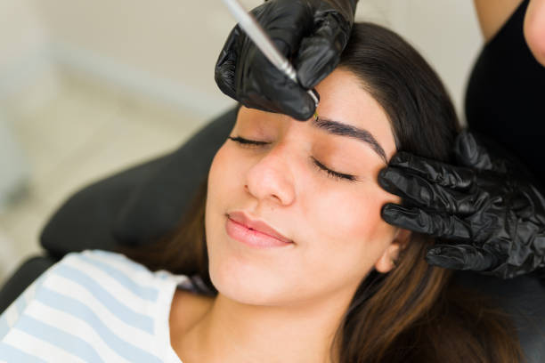 Attractive woman getting a microblading brow service Gorgeous hispanic woman relaxing and smiling while in the beauty salon for an eyebrow microblading service microblading  stock pictures, royalty-free photos  images
