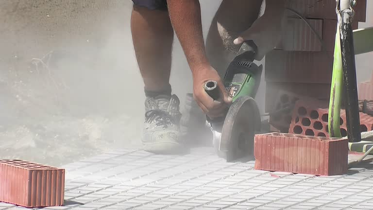 Bricklayer cutting with a grinder a pavement cobble of sidewalk outdoor