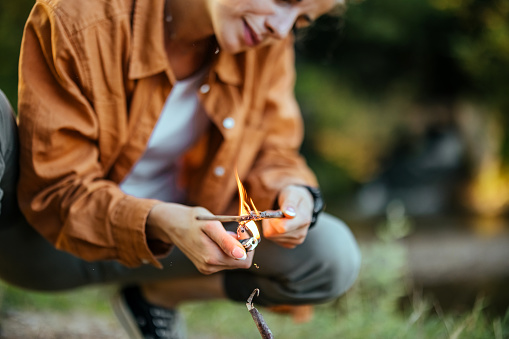 Young woman making fire in nature