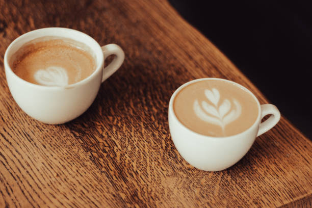 istock Two coffee cups on wooden table. Latte art concept. Coffee with milk in white cup. Breakfast table. Barista skill in making coffee art. Morning drinks. 1674518468