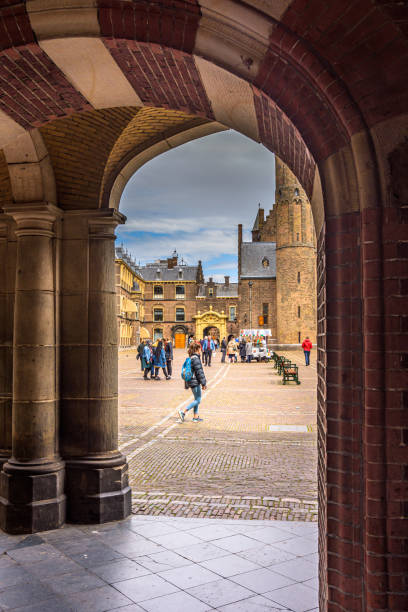 The Hague, Netherlands - May 10, 2019: View of the Binnenhof square in the center of politics in The Hague. People walk across the square on a sunny day, The ice cream man sells his ice cream to the people