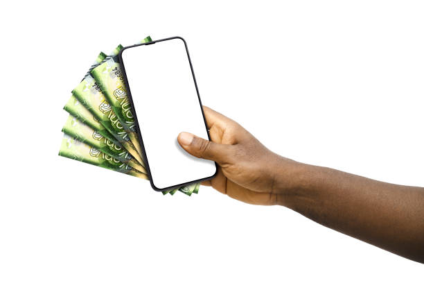 istock Black hand holding mobile phone with blank screen and Kenyan shilling notes 1674556230