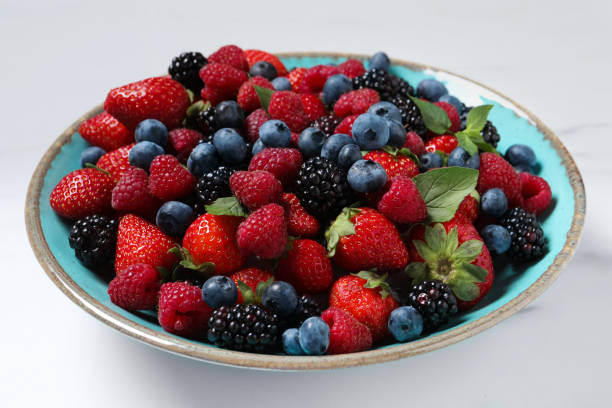 istock Many different fresh ripe berries in bowl on white table, closeup 1674563766