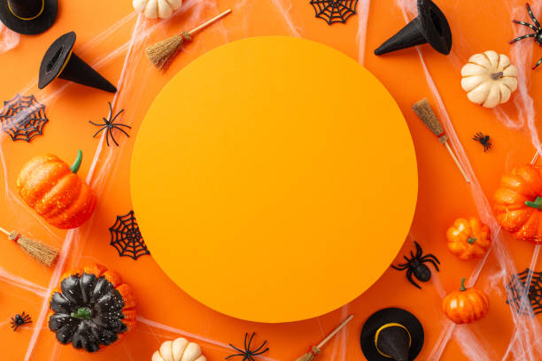 istock Vibrant Halloween celebration vision. Bird's-eye view image featuring pumpkins, witch hats and brooms and Halloween-themed elements on isolated orange surface with space for text or marketing use 1674566480