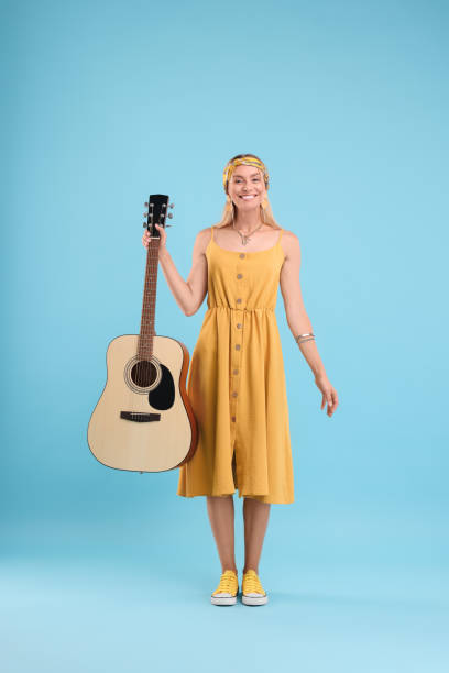 istock Happy hippie woman with guitar on light blue background 1674581212