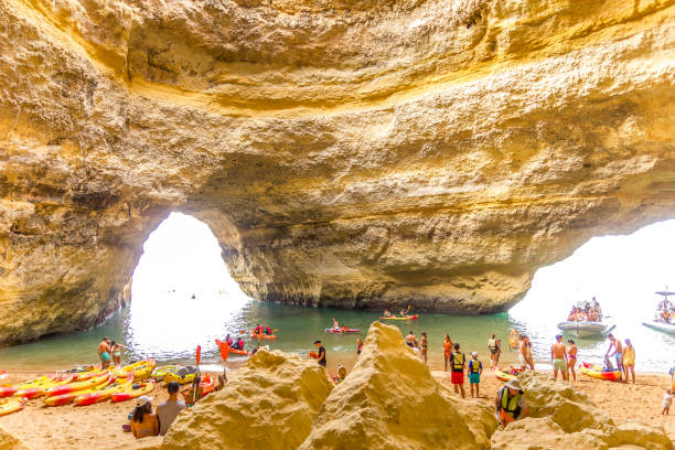 People visiting the Benagil cave, Algarve, Portugal Algarve, Portugal - 26 August, 2023: People visiting the Benagil cave. The beautiful site is famous by its beach and the light coming from a large hole in the roof. beautiful beach in carvoeiro algarve portugal stock pictures, royalty-free photos & images
