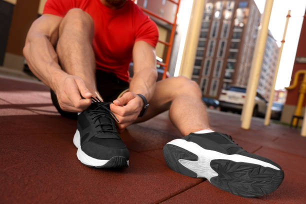 istock Man tying shoelaces before training at outdoor gym, closeup 1674589069