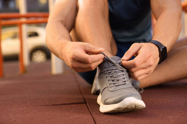 istock Man tying shoelaces before training at outdoor gym, closeup 1674590167