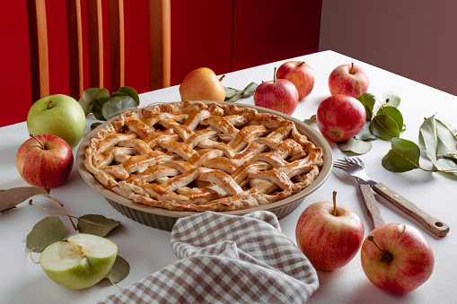 Homemade Apple Pie with fresh apples on white kitchen table. Thanksgiving traditional dessert ready to eat, Thanksgiving tart preparation, autumn bakery. Crispy weather sweets. Recipe