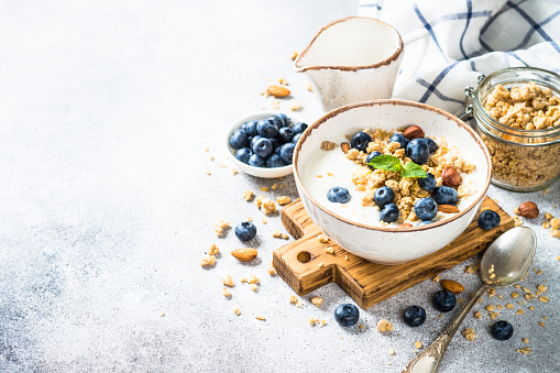 Yogurt with granola and fresh berries at stone table. Healthy food, snack or breakfast.