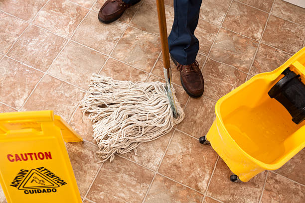 Caution sign, janitor man mopping floor of retail store. Cleaning. Caution sign in view as man mops floor of retail outlet.  Janitorial services. Caretaker. commercial janitor stock pictures, royalty-free photos & images