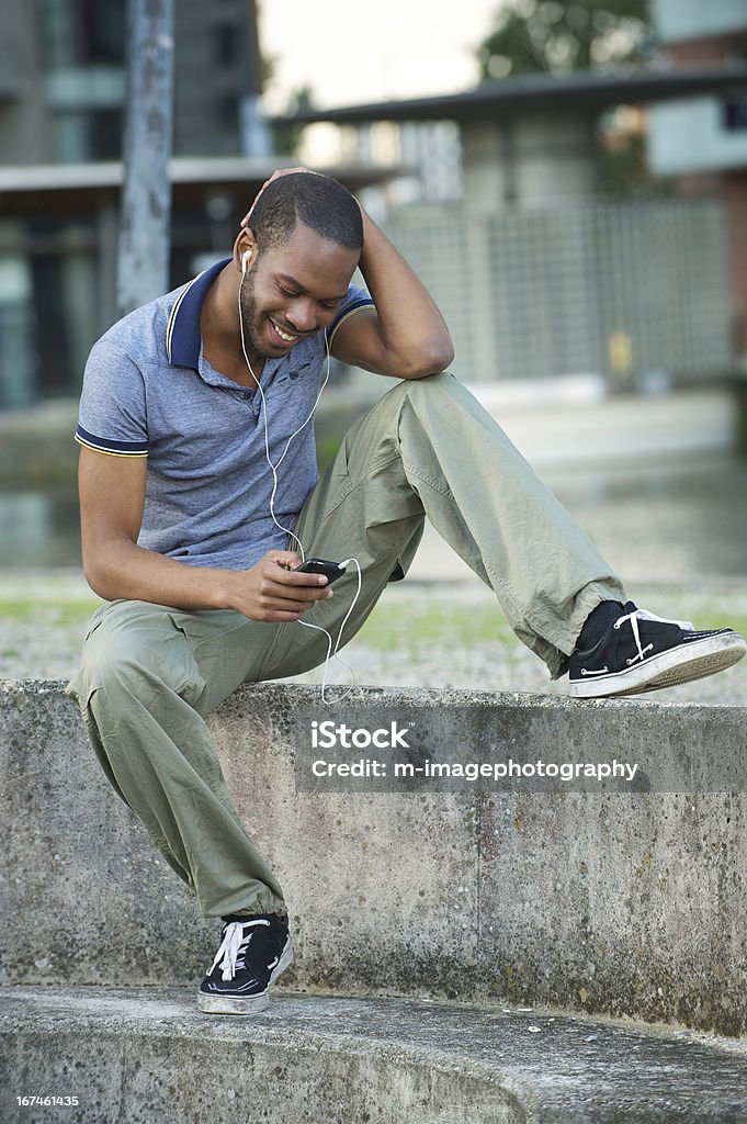 African American Man Listening to Music Handsome young African American man enjoying music on his mp3 player Adult Stock Photo