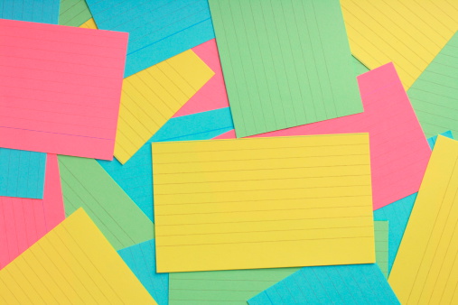 Several lined note or speech prompt cards in various colors;yellow,green,blue and pink arranged on a flat surface to form a colorful background