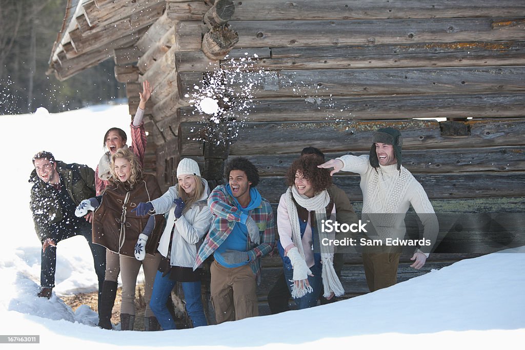 Portrait de souriant amis lancer des boules de neige en face de la cabine - Photo de Neige libre de droits