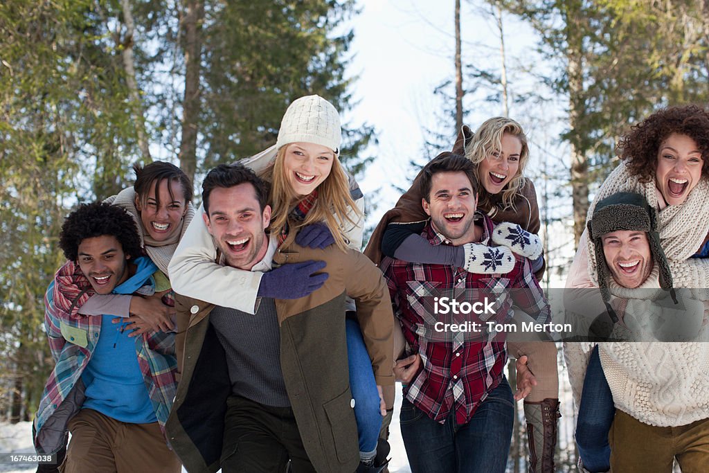 Enthusiastic couples piggybacking in snowy woods  20-24 Years Stock Photo