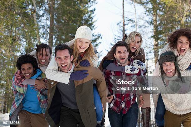 Enthusiastic Couples Piggybacking In Snowy Woods Stock Photo - Download Image Now - 20-24 Years, 25-29 Years, 30-34 Years