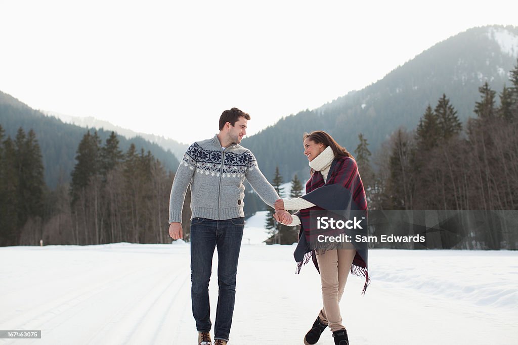 Sorrindo casal de mãos dadas e andando no campo de neve - Foto de stock de Andar royalty-free