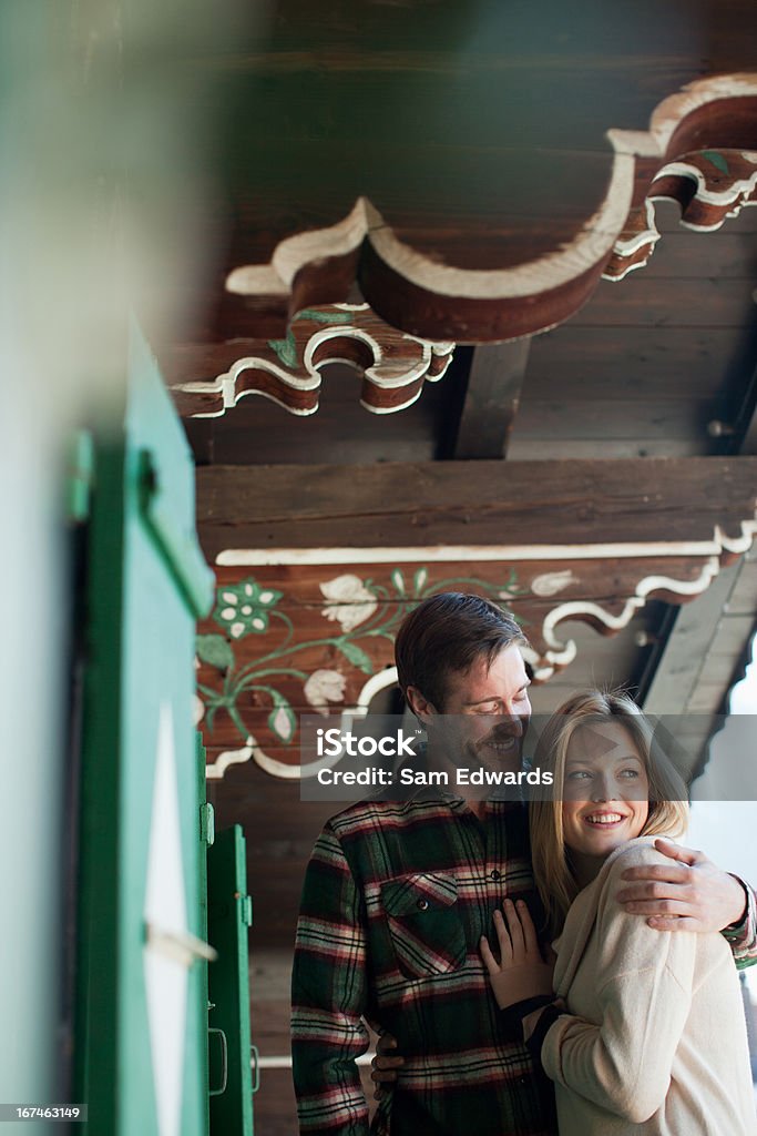 Smiling couple hugging on cabin porch  25-29 Years Stock Photo