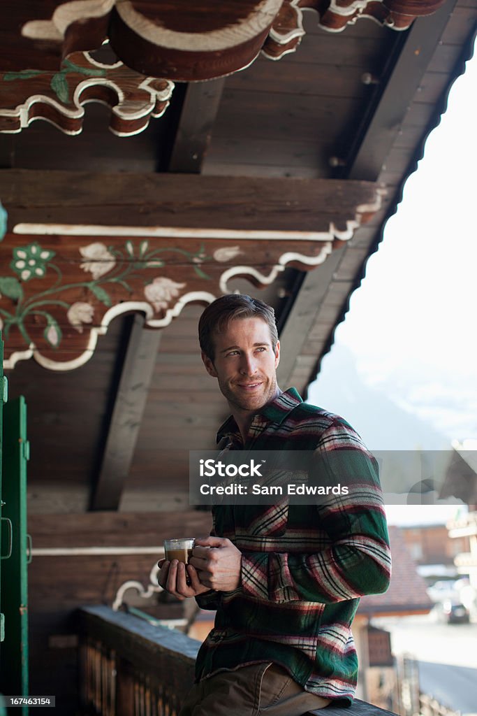 Homem sorridente tomando café na varanda da cabine - Foto de stock de 30 Anos royalty-free