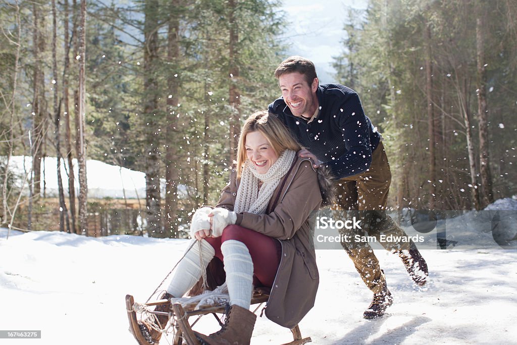 Smiling couple sledding in snow  Fun Stock Photo