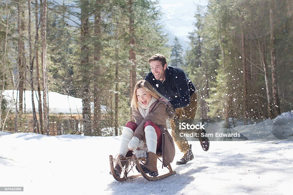 Sonriendo par de paseos en trineo en la nieve - Foto de stock de 25-29 años libre de derechos