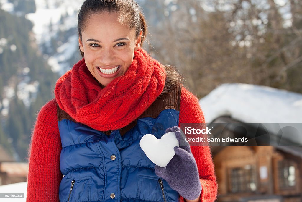Retrato de mujer sonriente sosteniendo corazón en forma de bola de nieve - Foto de stock de 30-34 años libre de derechos