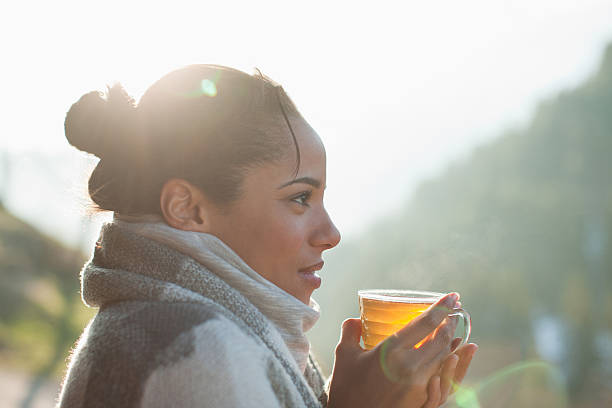 primo piano di donna sorridente bere tè all'aperto - hair bun asian ethnicity profile women foto e immagini stock