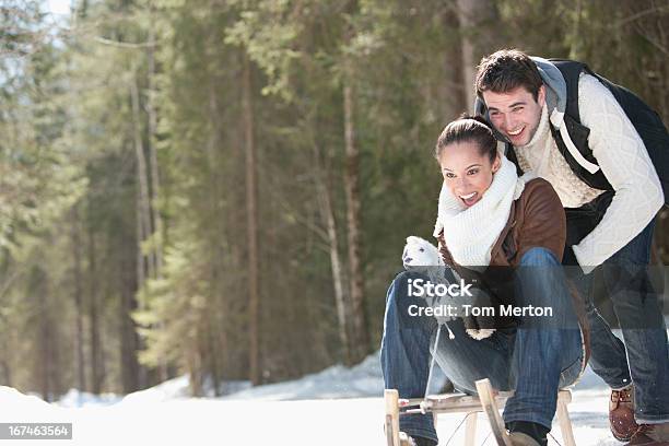 Smiling Couple Sledding In Snowy Field Stock Photo - Download Image Now - 20-24 Years, 30-34 Years, 30-39 Years