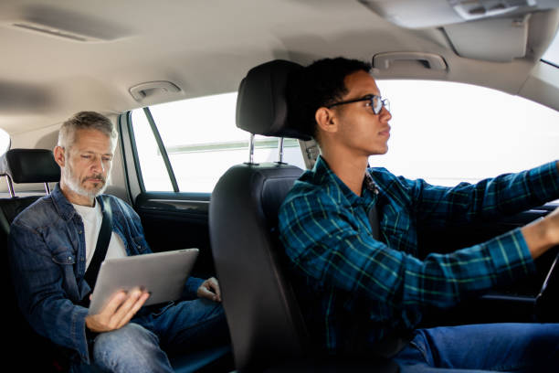 istock Taxi driver driving a man while he's working online 1674655693