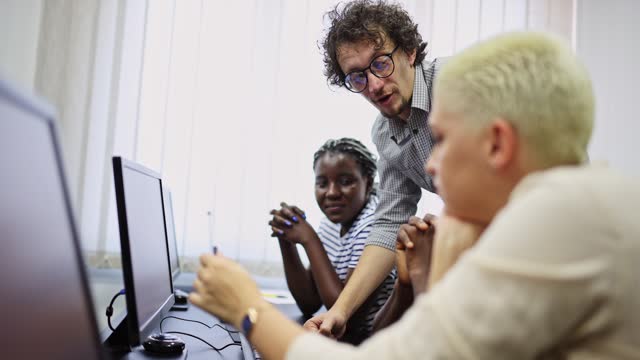 Male Teacher Helping Students In A Programming Class
