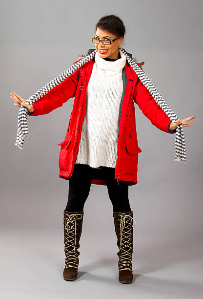 Fashion model posing in red jacket and neckpiece on grey background.