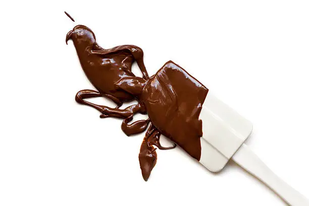 Melted chocolate splashing from a spatula, isolated on white background.