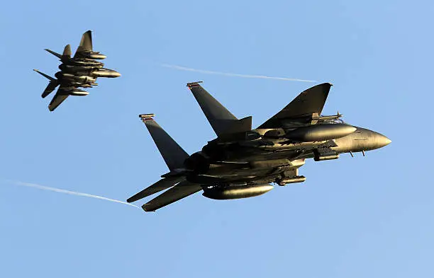 A pair of F-15E Strike Eagle aircraft breaking away at sunset