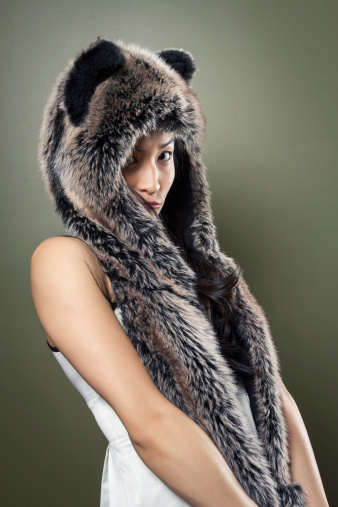 A shy young Chinese woman wearing a fur animal hat.