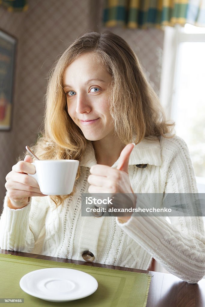 Menina com uma xícara de café mostrando polegares para cima O sinal - Foto de stock de Adulto royalty-free