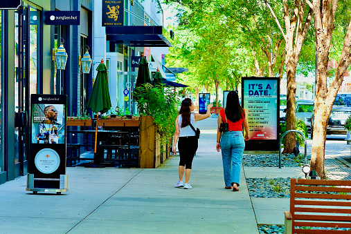 Fairfax, Virginia, USA - September 5, 2023: Two women walk in the Mosaic District, a popular multi-use development containing luxury condominiums, apartments, retail shopping, restaurants, cafes, a theater, and open space.