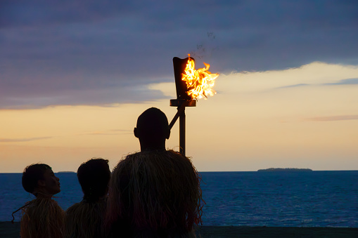Denarau Fiji - September 3 2023; Lighting the flame at dusk local Fijian man and boys in silhouette
