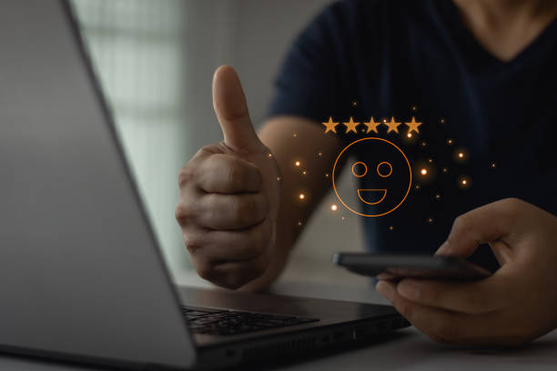 Customer service experiences and satisfaction review concept. Happy businessman using smartphone to give five star rating and thumbs up right with awesome smile icon for online satisfaction surveys.
