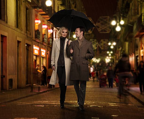 elegante coppia con ombrello da pioggia all'aperto di sera - barcelona city night street foto e immagini stock