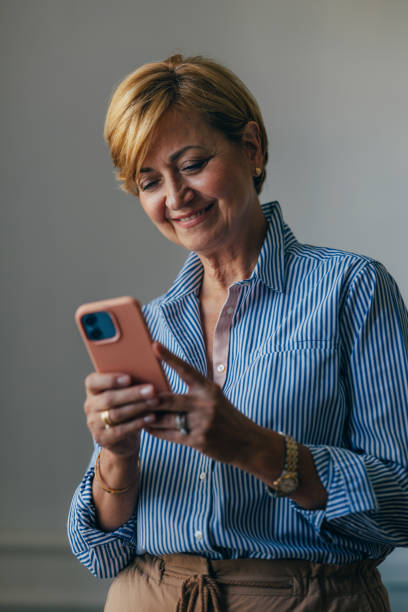 istock Happy Beautiful Businesswoman Using Her Mobile Phone while Standing 1674852789