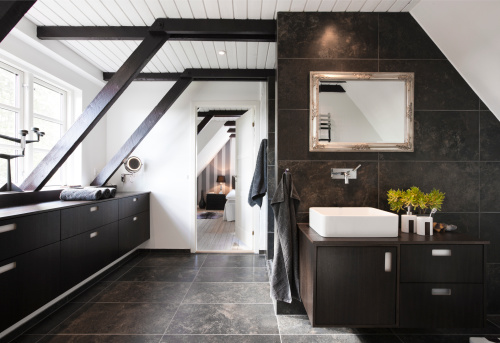 Bathroom in conjunction with bedroom. Structural beams, dark wood and granite tiles.