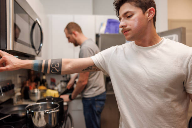 istock Kitchen master, Latino man cooking with father. Young Hispanic man with mustache and military tattoo cooking, looking down and waiting. Mature man on blurred background. Close up 1674872032