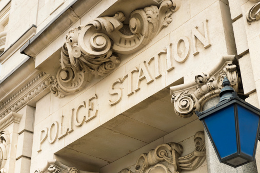 A traditional sign in the stonework above the entrance to a  police station, and a blue police lantern.