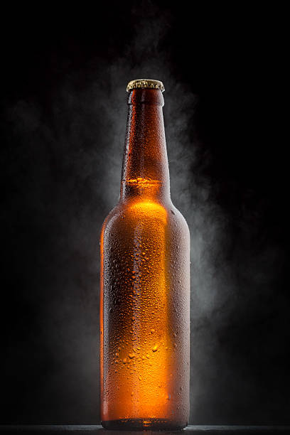 Cold beer bottle with drops, frost and vapour on black stock photo